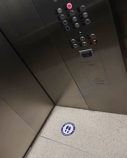 Photo of elevator floor with sticker marking social distancing