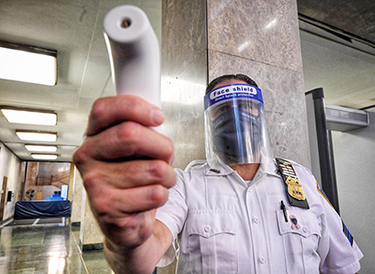 Court Officer uses thermometer to check person's temperature