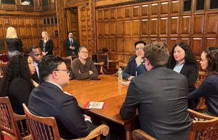 Law school students hold a discussion around a table in a wood-paneled room