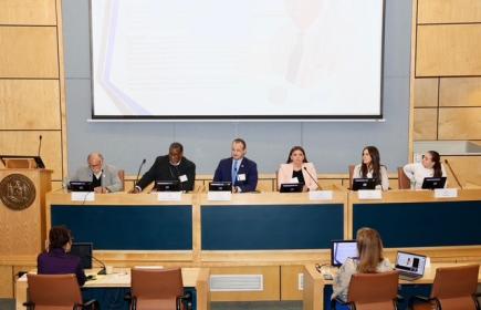 Panel of speakers sits beneath a projector screen