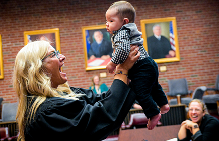 Photo of a Family Court Judge holding up an infant