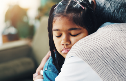 Photo of a young girl being hugged by an older adult