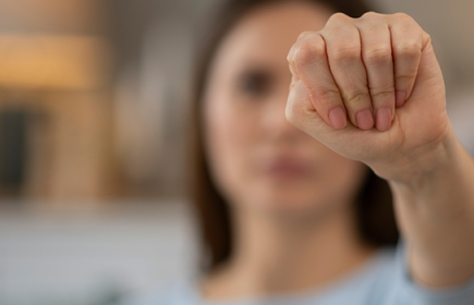 Photo of a woman using the hand signal for needs help
