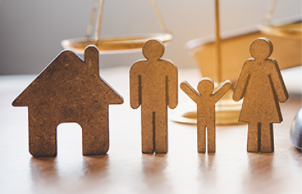 symbolic wooden figures representing a family and a house placed in front of the scales of justice