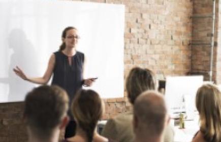 Woman standing in front of a whiteboard, conducting a training