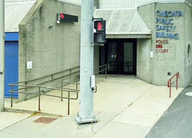 Description of photo: A full view of the entrance. There is a ramp on the sidewalk that leads to the left door that has ADA signage.