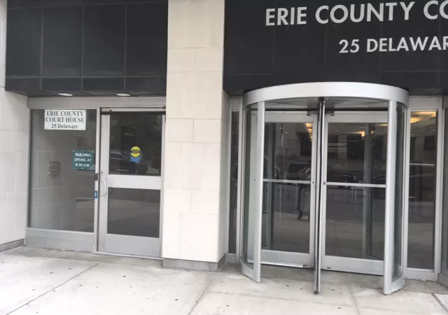 Description of photo: The main entrance of Erie County Court. There is a revolving door to the right and a single automatic door to the left.