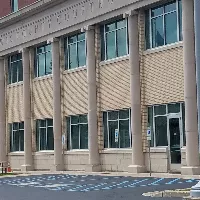 An area of the parking lot with ADA-accessible parking directly in front of an entrance to the building. The entrance can be accessed from the street level.