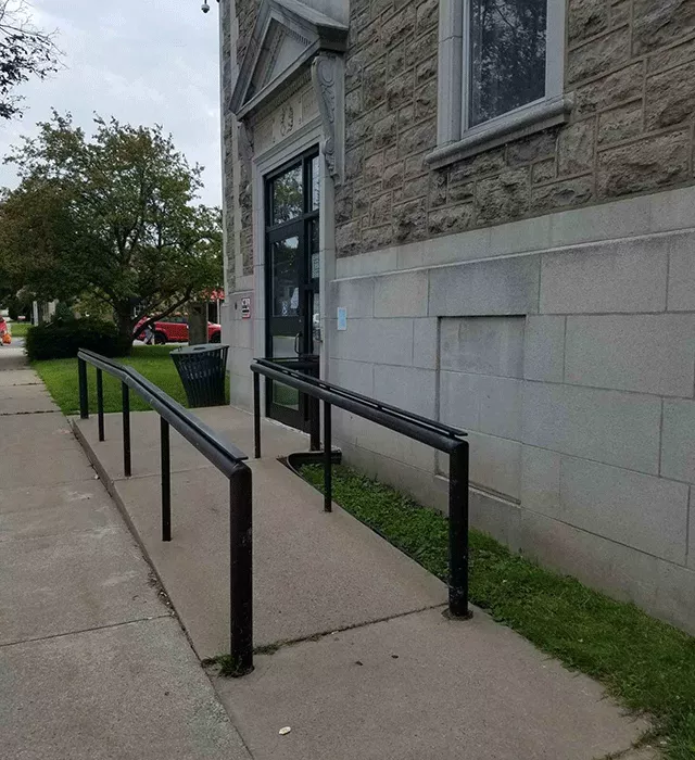 Description of photo: A side view of the entrance to the court facility. There is a ramp that is accessed toward the right that leads to the doors.