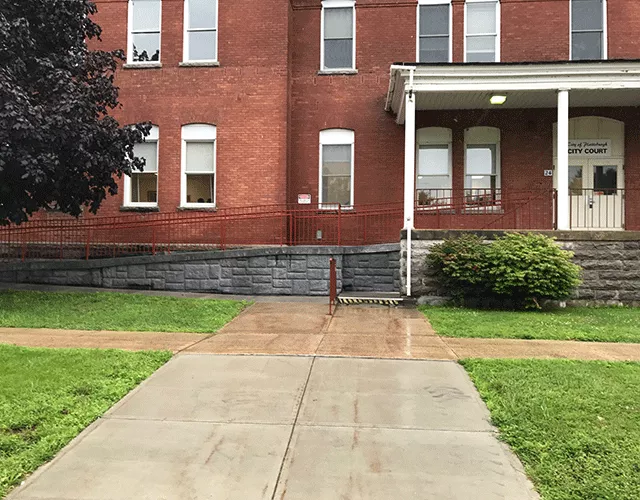 Description of photo: The photo is of a walkway that leads to stairs on the right side. The ramp is on the left and leads to the double door entrance.