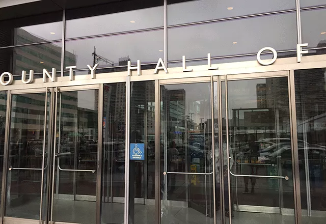 Two sets of double doors to enter the facility. In between the double doors is ADA signage.