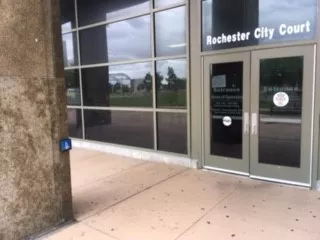 The courthouse with a double door entrance. Prior to reaching the doors, on the left column is a push button to open the automatic door.