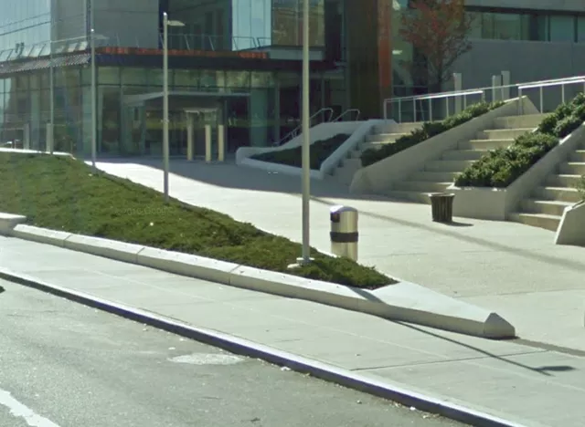 A walkway leading to the entrance of the Courthouse. The sloped walkway is accessed from the sidewalk and is lined with light posts.