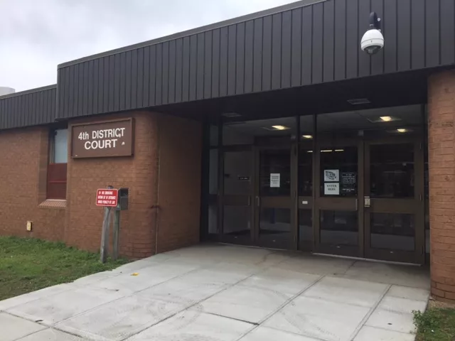 Courthouse with two sets of double doors. They are both accessed from a walkway. There is a '4th District Court' sign on the left side of the building.