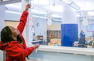 a person adjust hanging rabbit decorations inside childcare center
