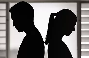 A silhouette of a man and a woman standing back-to-back