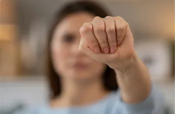 shows a signal to ask for help during domestic violence, known as the "Signal for Help" gesture, where the thumb is tucked into the palm and the fingers are closed over it. 