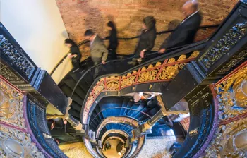 Photo of a group of adults descending an ornate spiral staircase inside a courthouse.