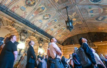Photo of a group of people looking up at an intricate mosaic tiled ceiling
